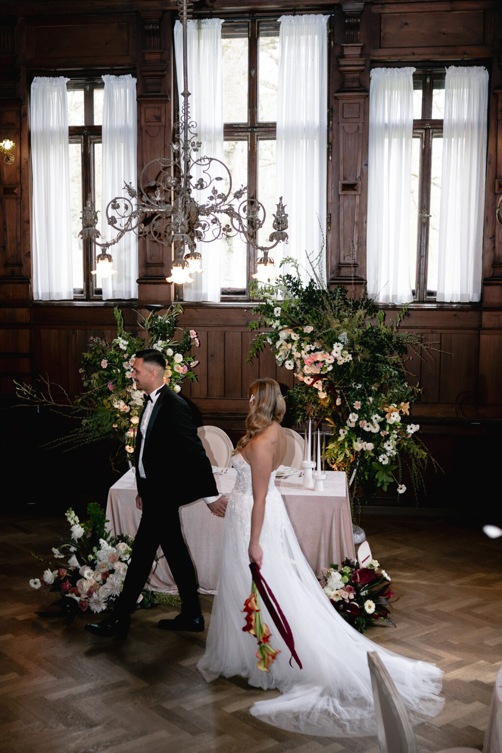 Heiraten in Bayern. Brautpaar geht zum Hochzeitstisch. Elegante Hochzeiten mit Dekoration und Blumen von Oh-Moments.