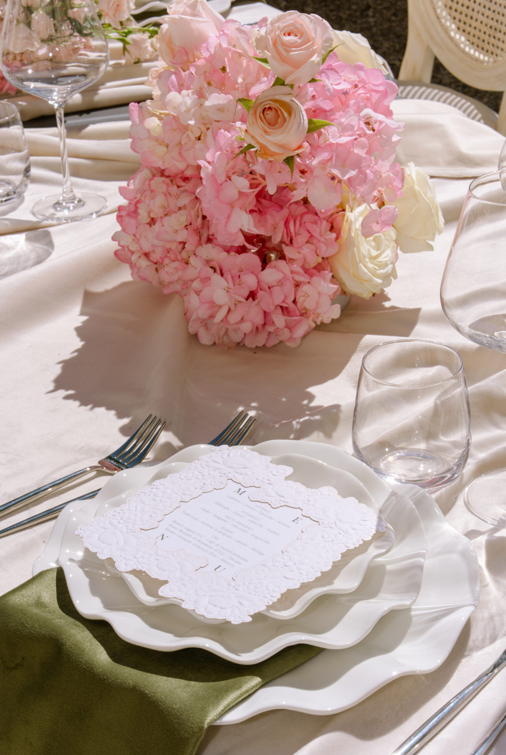 Elegantes Blumengesteck mit rosa Hortensien und Rosen auf weißem Hochzeitstisch
