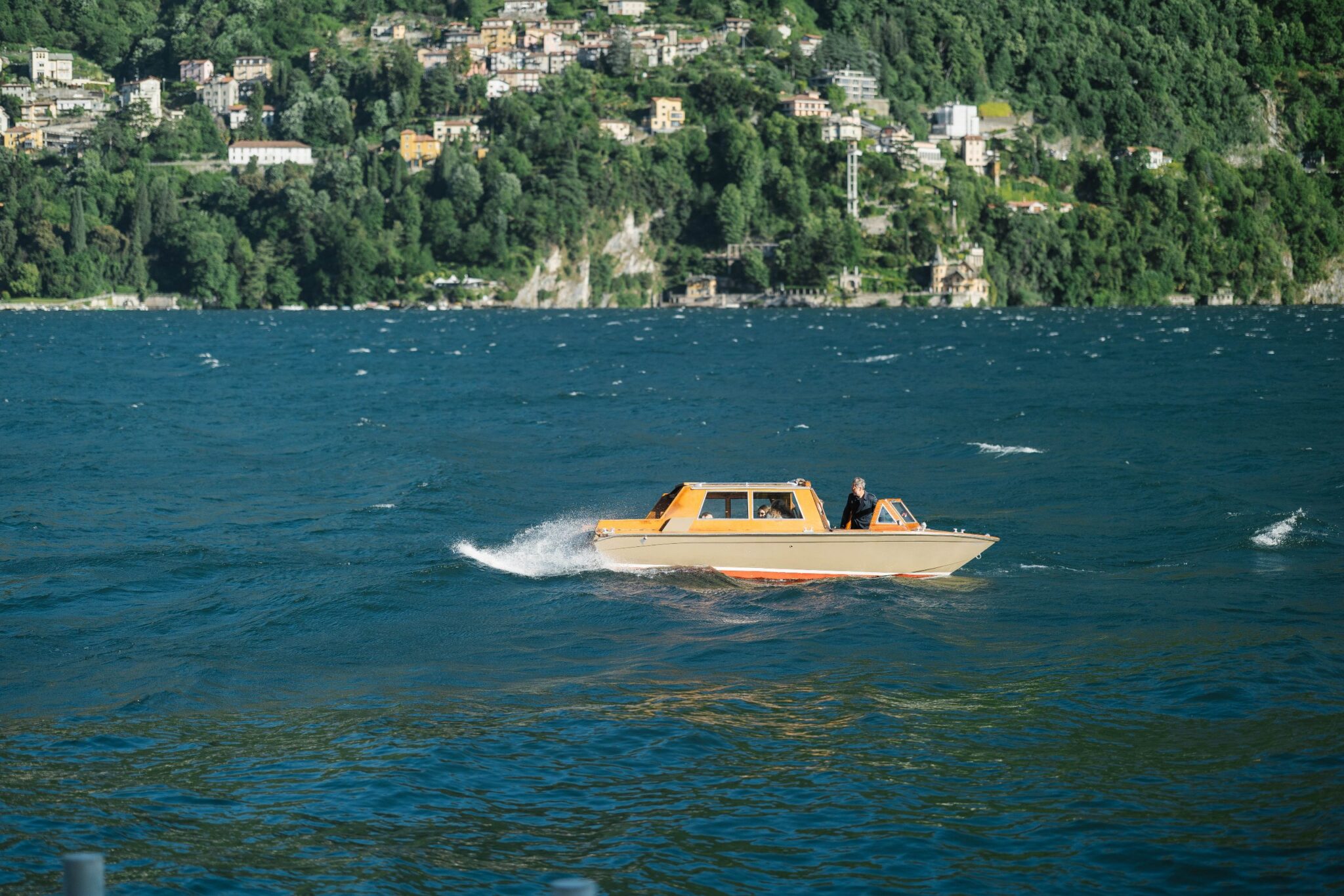 Classic wooden boat on Lake Como with green shoreline