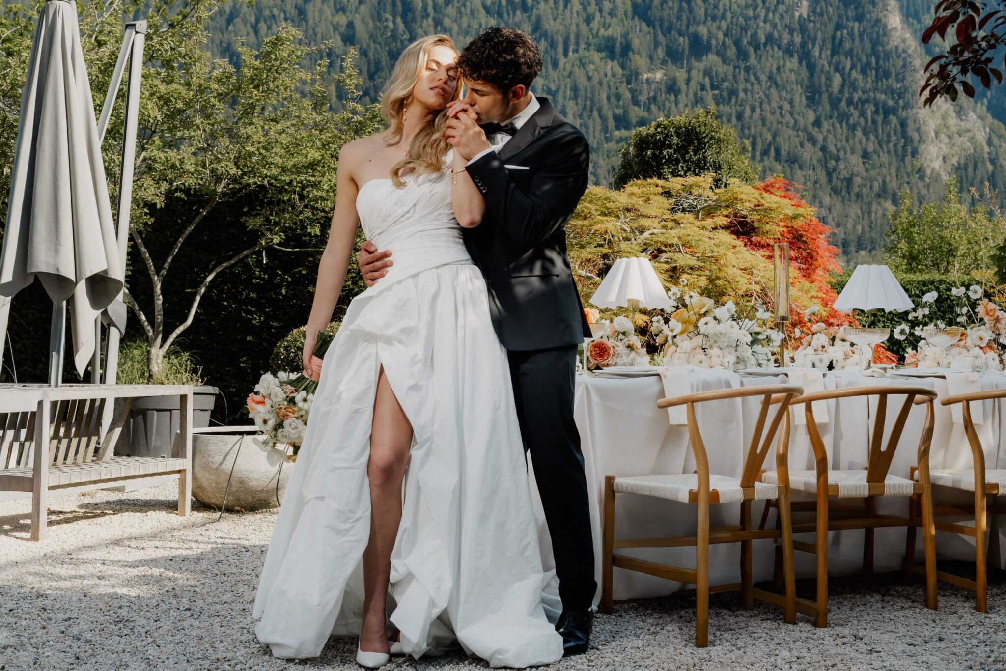 Bride and groom at a decorated wedding table in the garden of a glass pavilion in Switzerland
