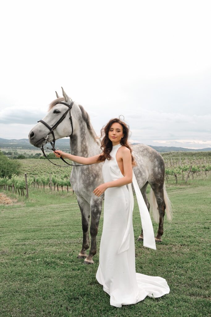 Bride with horse in front of the distant sky in Tuscany